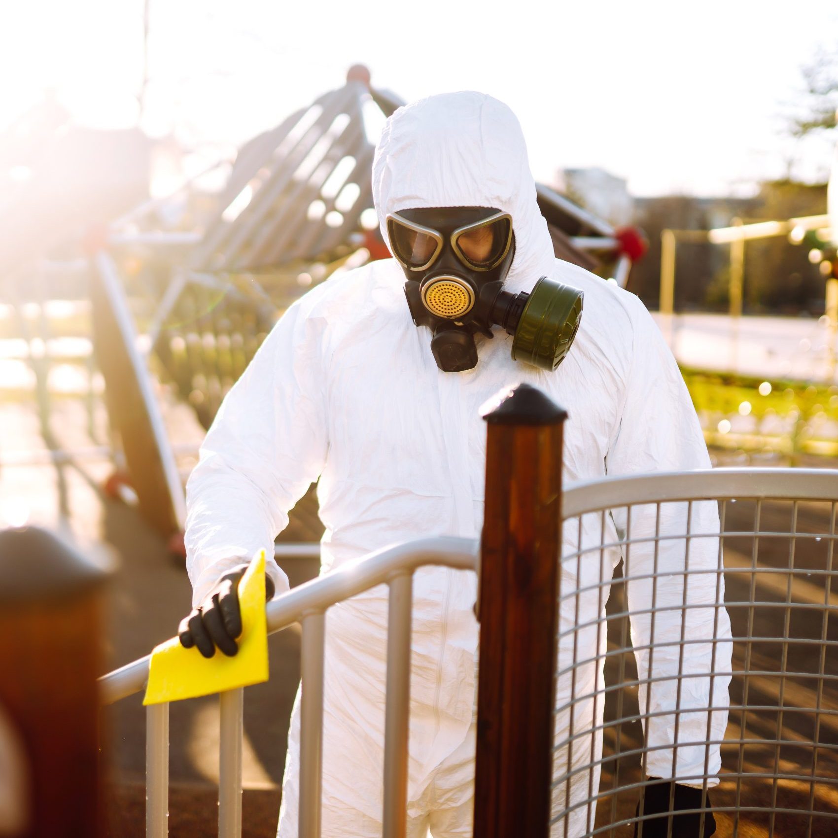 Man wearing protective suit washes and disinfecting playground to preventing the spread of epidemic
