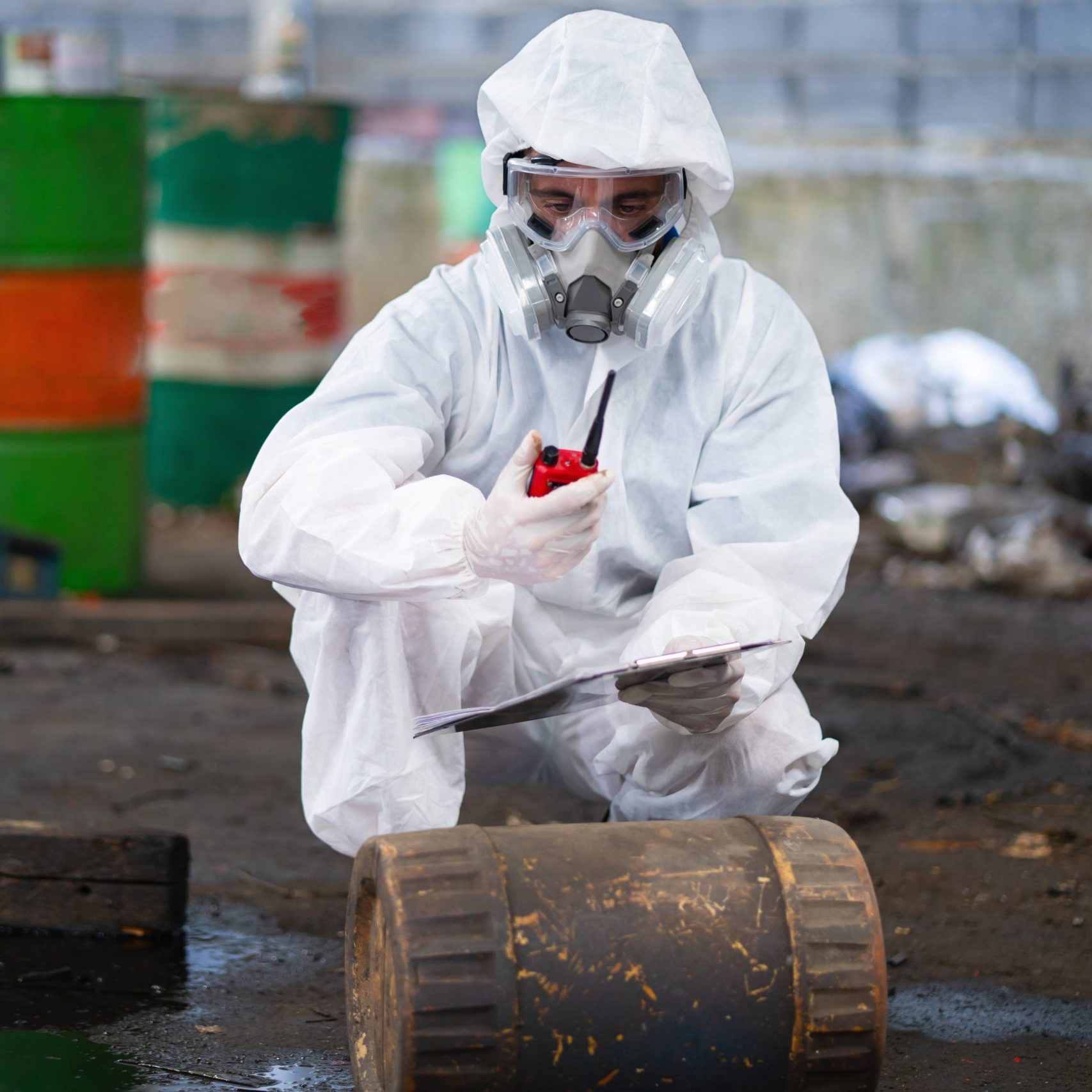 man in hazmat suit is examining barrel