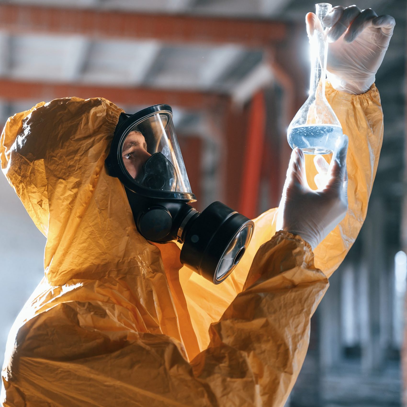 Examining radioactive liquid. Man dressed in chemical protection suit in the ruins of the post apocalyptic building